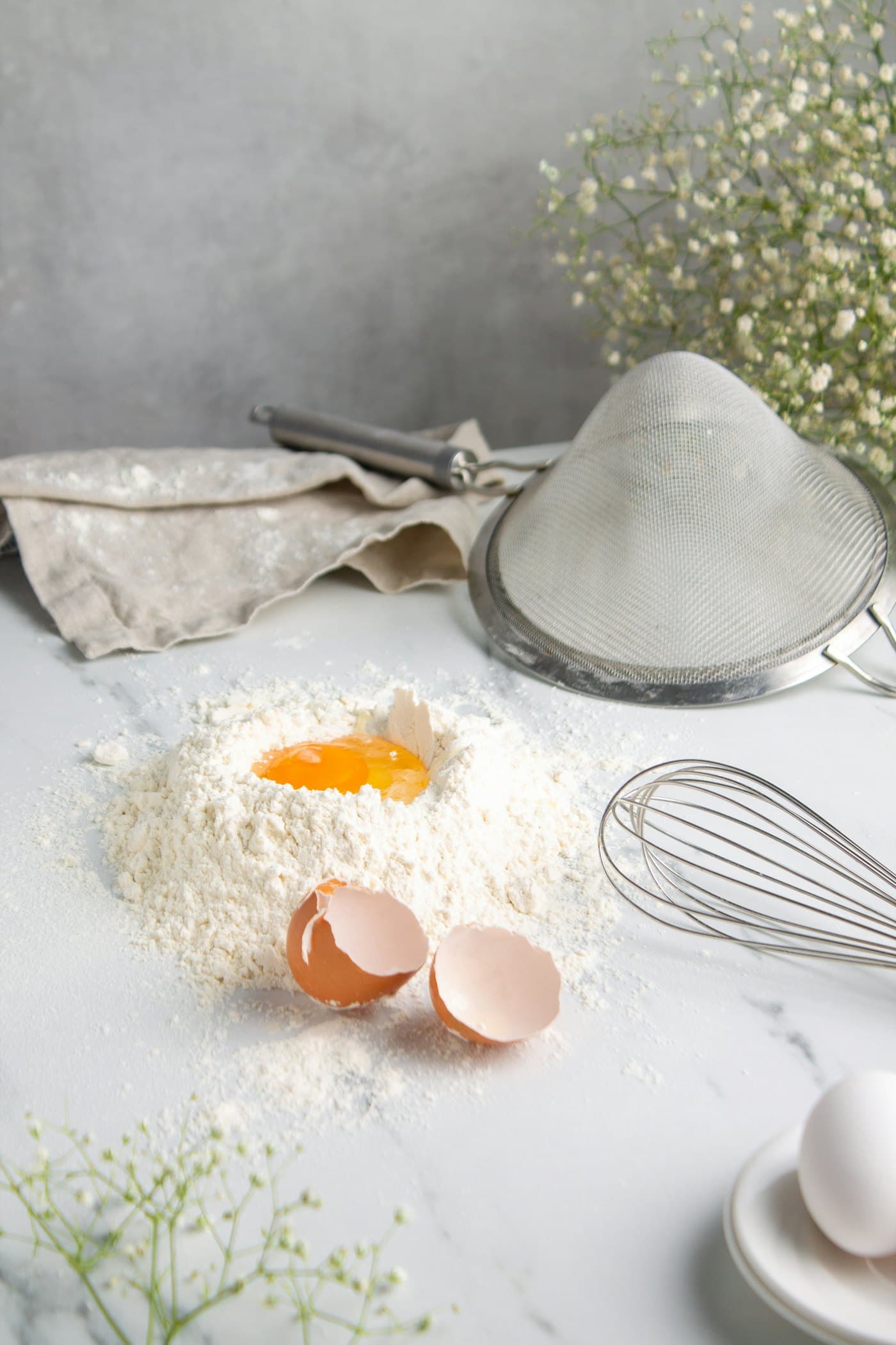 Flour, eggs and a whisk on a pale worktop